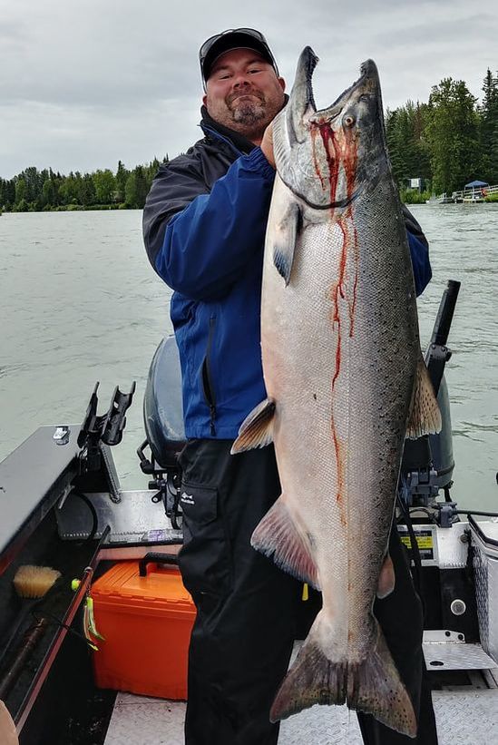 Fishing guide holds up a very large king salmon caught on a fishing charter in Autum.