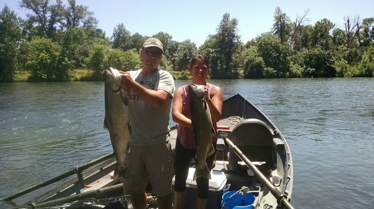 Two guests each hold up their salmon and steelhead caught on the Rogue River.